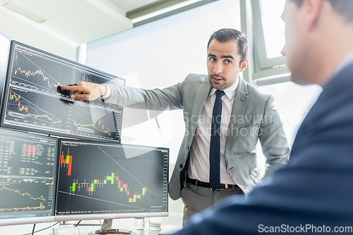 Image of Stock brokers looking at computer screens, trading online.