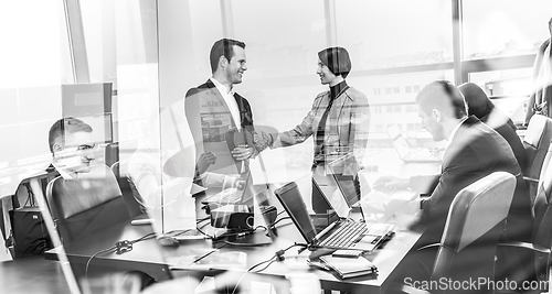 Image of Confident business people shaking hands in moder corporate office.