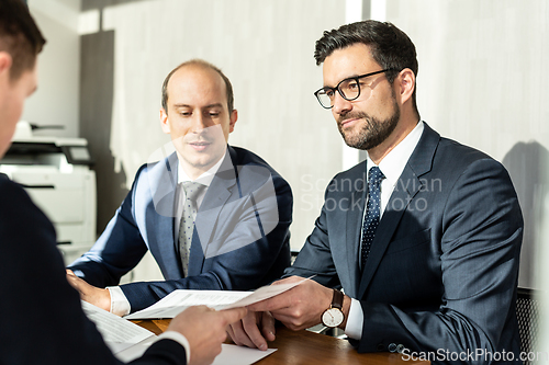 Image of Group of confident successful business people reviewing and signing a contract to seal the deal at business meeting in modern corporate office.