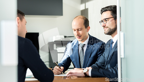 Image of Group of confident successful business people reviewing and signing a contract to seal the deal at business meeting in modern corporate office.