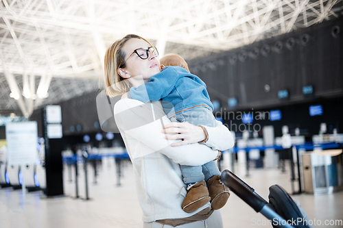 Image of Motherat happily holding and lifting his infant baby boy child in the air after being rejunited in front of airport terminal station. Baby travel concept.