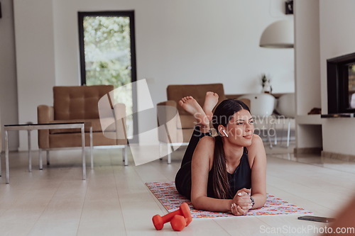 Image of Young woman resting after online training while lying on the living room floor