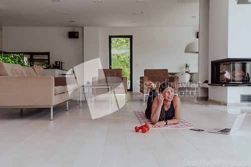 Image of Young woman resting after online training while lying on the living room floor