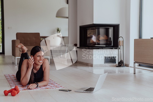 Image of Young woman resting after online training while lying on the living room floor