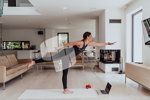 Image of Young Beautiful Female Exercising, Stretching and Practising Yoga with Trainer via Video Call Conference in Bright Sunny House. Healthy Lifestyle, Wellbeing and Mindfulness Concept.