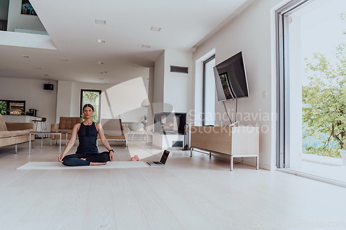 Image of Young Beautiful Female Exercising, Stretching and Practising Yoga with Trainer via Video Call Conference in Bright Sunny House. Healthy Lifestyle, Wellbeing and Mindfulness Concept.