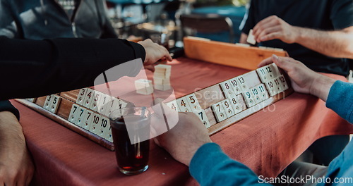 Image of A group of men drink traditional Turkish tea and play a Turkish game called Okey