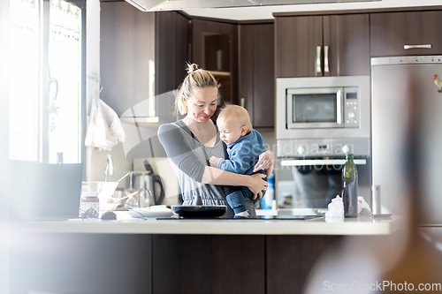 Image of Happy mother and little infant baby boy making pancakes for breakfast together in domestic kitchen. Family, lifestyle, domestic life, food, healthy eating and people concept.