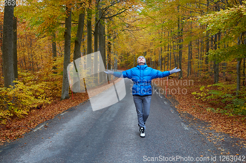 Image of Young woman posing in the autumn forest on the road.
