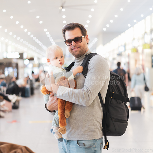 Image of Father traveling with child, holding his infant baby boy at airport terminal waiting to board a plane. Travel with kids concept.