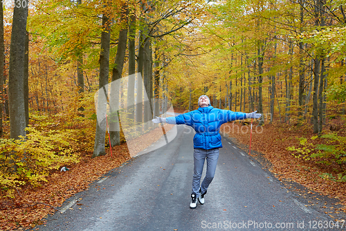 Image of Young woman posing in the autumn forest on the road.