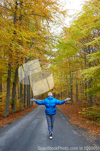 Image of Young woman posing in the autumn forest on the road.