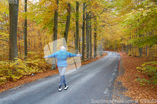 Image of Young woman posing in the autumn forest on the road.