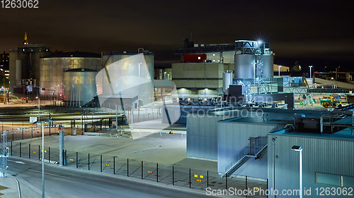 Image of Modern grain terminal at night. Metal tanks of elevator. Grain-drying complex construction. Commercial grain or seed silos at seaport. Steel storage for agricultural harvest