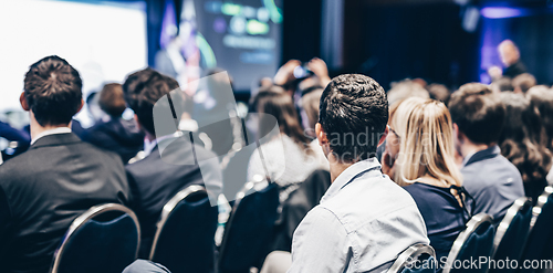 Image of Speaker giving a talk in conference hall at business event. Rear view of unrecognizable people in audience at the conference hall. Business and entrepreneurship concept.