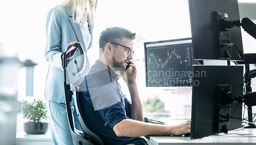 Image of Stock broker business team trading online watching charts and data analyses on multiple computer screens in modern corporate work station office.