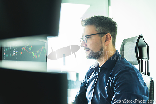 Image of Stock broker trading online watching charts and data analyses on multiple computer screens.