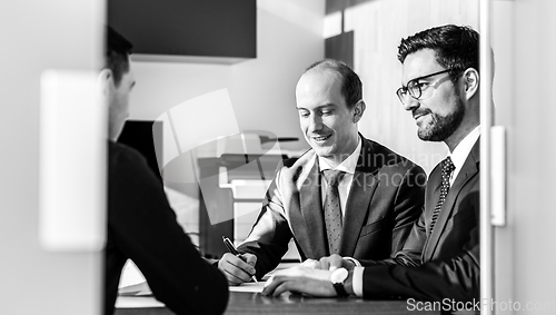 Image of Group of confident successful business people reviewing and signing a contract to seal the deal at business meeting in modern corporate office.