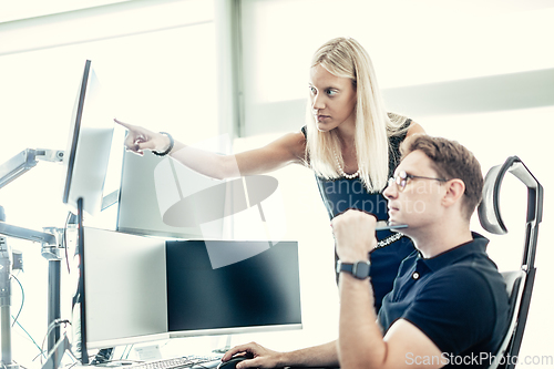 Image of Stock broker business team trading online watching charts and data analyses on multiple computer screens in modern corporate work station office.