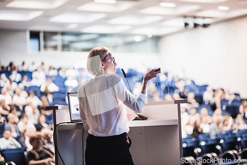 Image of Female speaker giving a talk on corporate business conference. Unrecognizable people in audience at conference hall. Business and Entrepreneurship event.