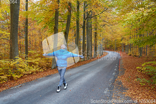 Image of Young woman posing in the autumn forest on the road.