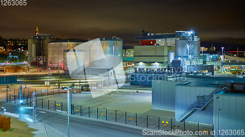 Image of Modern grain terminal at night. Metal tanks of elevator. Grain-drying complex construction. Commercial grain or seed silos at seaport. Steel storage for agricultural harvest