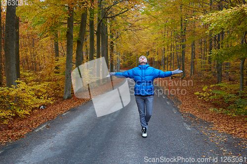 Image of Young woman posing in the autumn forest on the road.