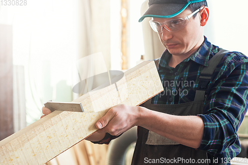 Image of The worker makes measurements of a wooden board