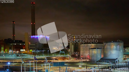 Image of Modern grain terminal at night. Metal tanks of elevator. Grain-drying complex construction. Commercial grain or seed silos at seaport. Steel storage for agricultural harvest