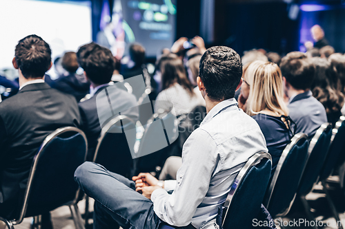 Image of Speaker giving a talk in conference hall at business event. Rear view of unrecognizable people in audience at the conference hall. Business and entrepreneurship concept.