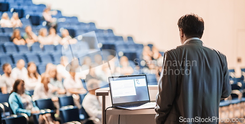 Image of Speaker giving a talk on corporate business conference. Unrecognizable people in audience at conference hall. Business and Entrepreneurship event.