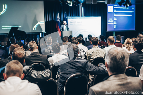 Image of Speaker giving a talk in conference hall at business event. Rear view of unrecognizable people in audience at the conference hall. Business and entrepreneurship concept.