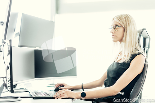 Image of Female financial assets manager, trading online, watching charts and data analyses on multiple computer screens. Modern corporate business woman concept.