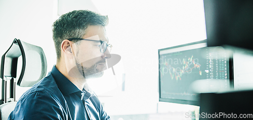 Image of Stock broker trading online watching charts and data analyses on multiple computer screens.