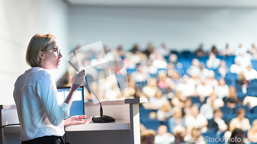 Image of Female speaker giving a talk on corporate business conference. Unrecognizable people in audience at conference hall. Business and Entrepreneurship event.