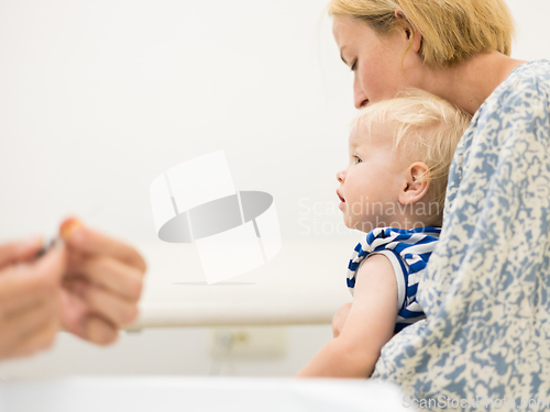 Image of Child beeing vaccinated by pediatrician in presence of his mother. Preventive vaccination against Diphtheria, whooping cough, tetanus, hepatitis, haemophilus influenzae, pneumococcus, poliomyelitis