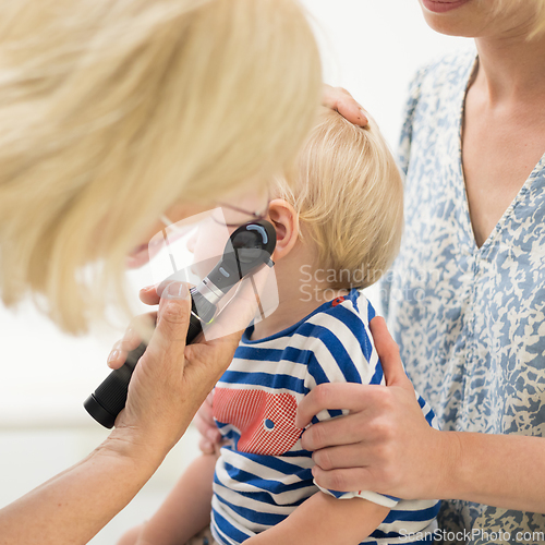 Image of Infant baby boy child being examined by his pediatrician doctor during a standard medical checkup in presence and comfort of his mother. National public health and childs care care koncept.