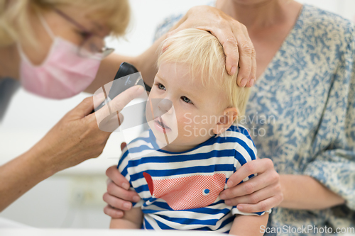 Image of Infant baby boy child being examined by his pediatrician doctor during a standard medical checkup in presence and comfort of his mother. National public health and childs care care koncept.