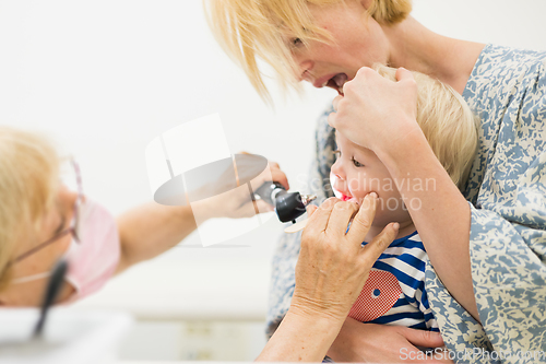 Image of Infant baby boy child being examined by his pediatrician doctor during a standard medical checkup in presence and comfort of his mother. National public health and childs care care koncept.