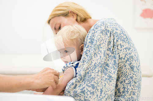 Image of Child beeing vaccinated by pediatrician in presence of his mother. Preventive vaccination against Diphtheria, whooping cough, tetanus, hepatitis, haemophilus influenzae, pneumococcus, poliomyelitis