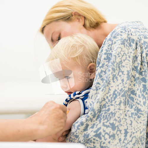 Image of Child beeing vaccinated by pediatrician in presence of his mother. Preventive vaccination against Diphtheria, whooping cough, tetanus, hepatitis, haemophilus influenzae, pneumococcus, poliomyelitis