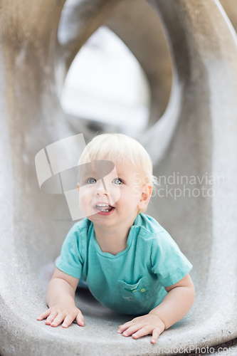 Image of Child playing on outdoor playground. Toddler plays on school or kindergarten yard. Active kid on stone sculpured slide. Healthy summer activity for children. Little boy climbing outdoors.