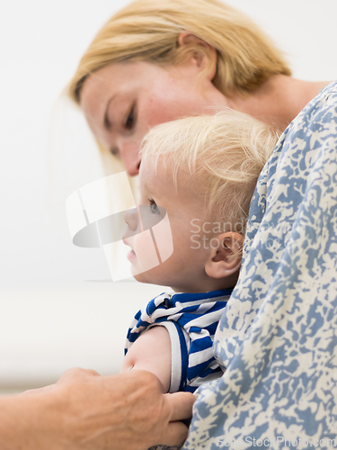 Image of Child beeing vaccinated by pediatrician in presence of his mother. Preventive vaccination against Diphtheria, whooping cough, tetanus, hepatitis, haemophilus influenzae, pneumococcus, poliomyelitis