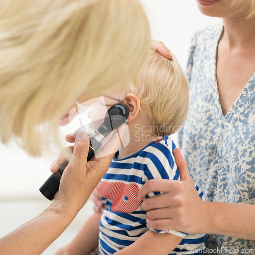 Image of Infant baby boy child being examined by his pediatrician doctor during a standard medical checkup in presence and comfort of his mother. National public health and childs care care koncept.