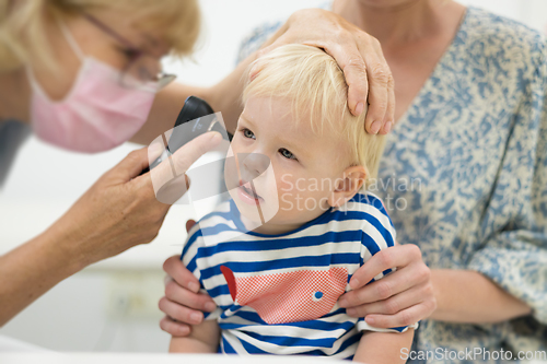 Image of Infant baby boy child being examined by his pediatrician doctor during a standard medical checkup in presence and comfort of his mother. National public health and childs care care koncept.