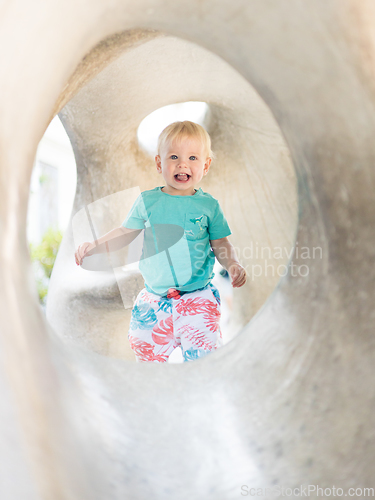 Image of Child playing on outdoor playground. Toddler plays on school or kindergarten yard. Active kid on stone sculpured slide. Healthy summer activity for children. Little boy climbing outdoors.