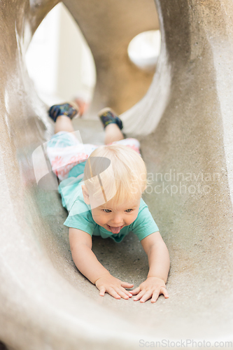 Image of Child playing on outdoor playground. Toddler plays on school or kindergarten yard. Active kid on stone sculpured slide. Healthy summer activity for children. Little boy climbing outdoors.