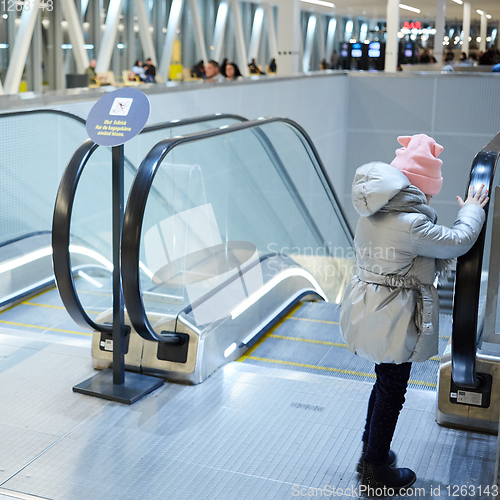 Image of Back view of child going on escalator background. Shopping mall, airport travel, love care, protection concept