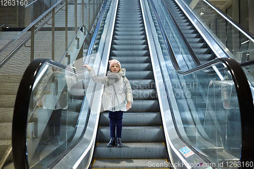 Image of From below shot of girl standing on moving stairs in terminal.