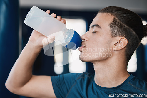 Image of Thirsty, fitness and a man drinking water after exercise at the gym for wellness and health. Hydration, young and a male athlete with a bottle for liquid after cardio, workout or training on a break